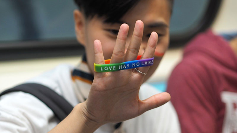 Man holding Love Has No Label wristband