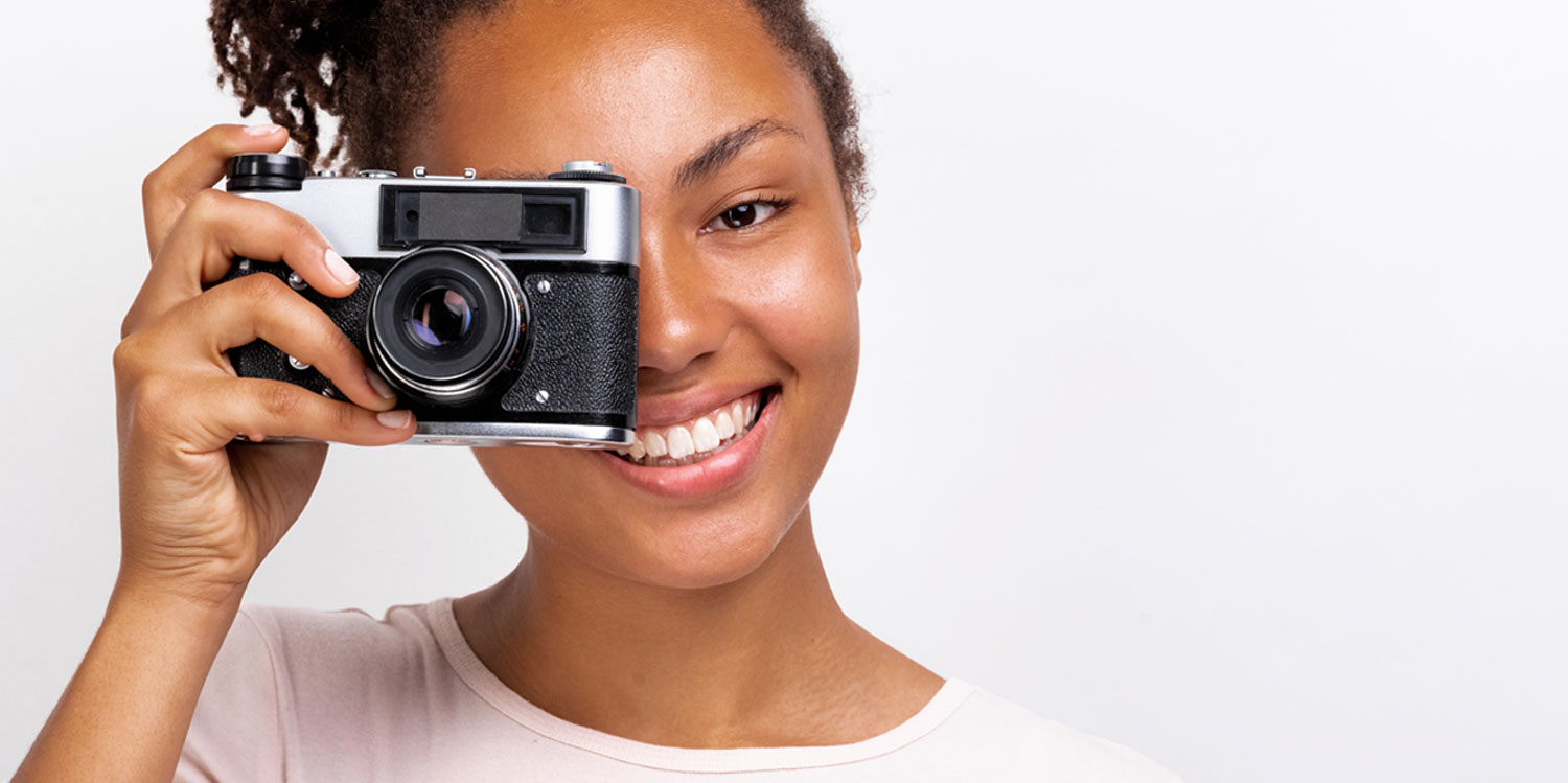 Woman of color holding a camera and smiling